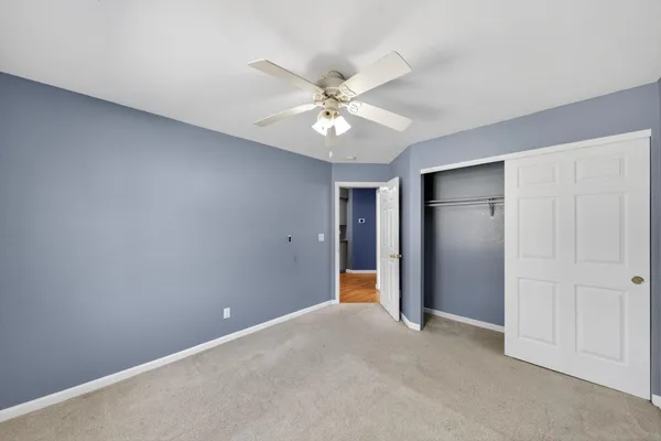 an empty room with closet and a ceiling fan