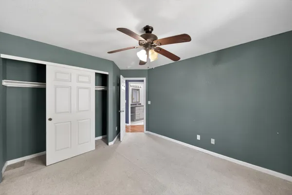 an empty room with closet and a ceiling fan