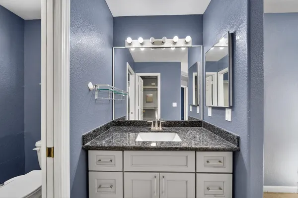 a bathroom with a granite countertop sink and a mirror
