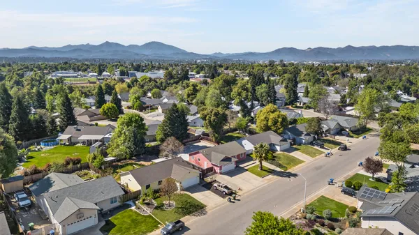 an aerial view of a city with lots of residential buildings and mountain view in back