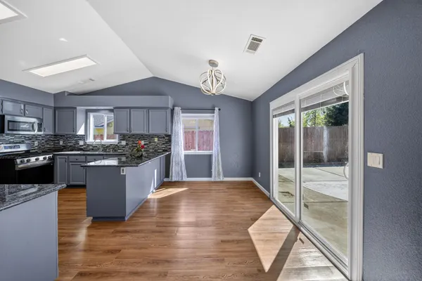 a large open kitchen with kitchen island a large window a sink and stainless steel appliances