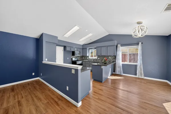 a kitchen with stainless steel appliances granite countertop a sink cabinets and wooden floor