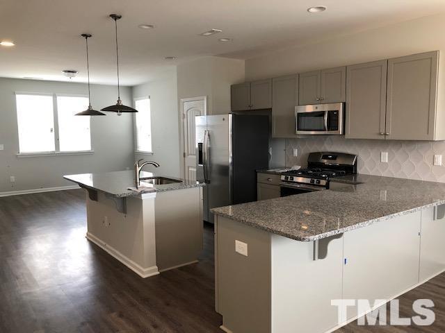 307 Devon Clfs Drive Wake Forest, NC 27587 - Photo 3 of 13 a kitchen with kitchen island a counter top space a sink cabinets and stainless steel appliances