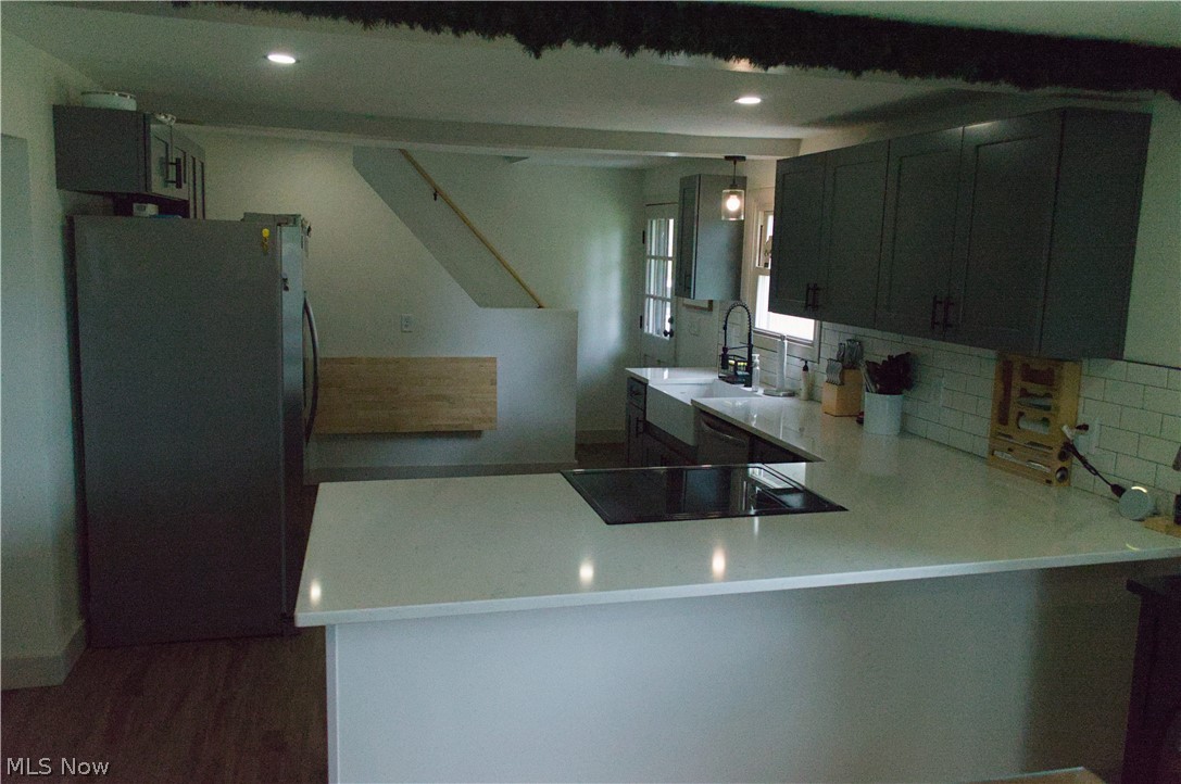 3187 Grenfall Road Barberton, OH 44203 - Photo 6 of 17 The kitchen features an integrated cooktop on the island, white countertops, dark gray cabinetry, and a white subway tile backsplash