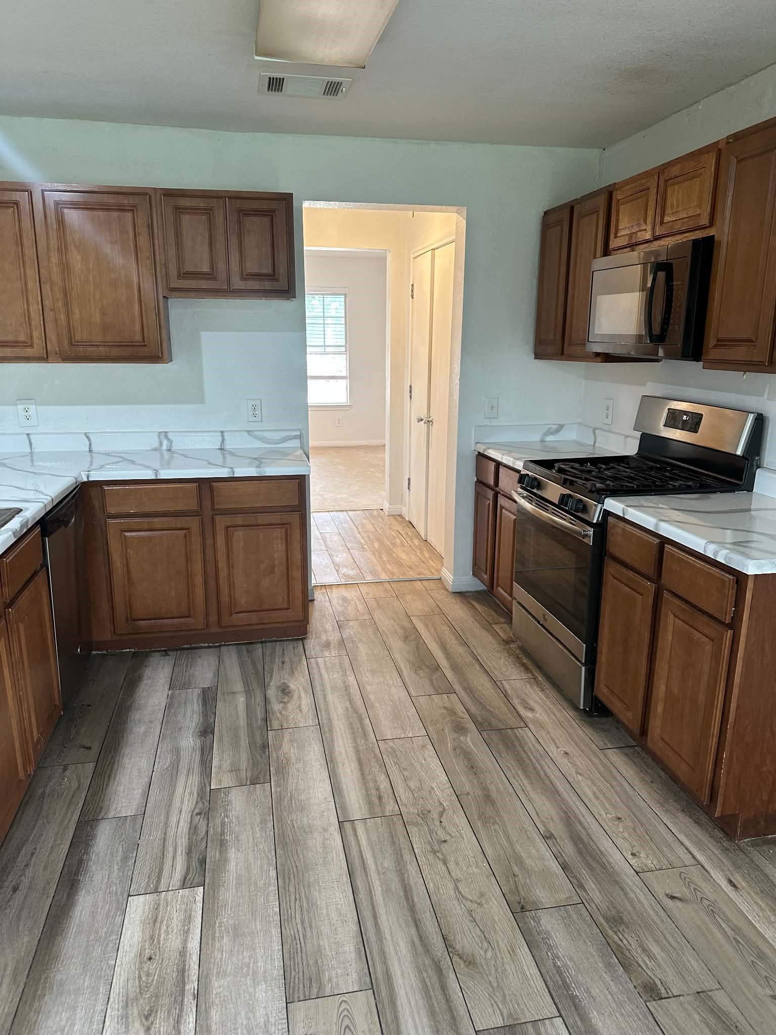18312 Crestwind Lane Elgin, TX 78621 - Photo 5 of 15 Modern kitchen with wood-look flooring and stainless steel appliances awaits culinary adventures.