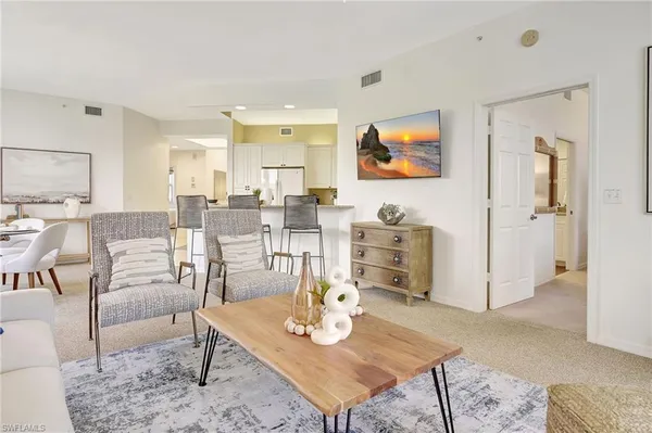 a living room with furniture a rug and kitchen view