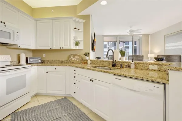 a kitchen with granite countertop white cabinets and white appliances