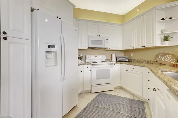 a kitchen with white cabinets and white appliances