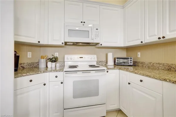 a kitchen with granite countertop white cabinets and white appliances