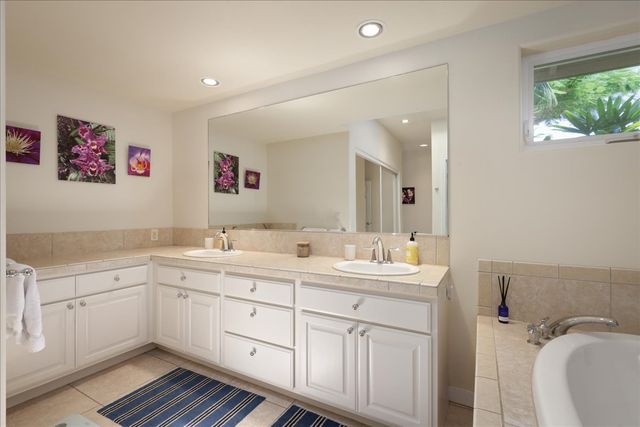 a spacious bathroom with a double vanity sink a mirror and a window