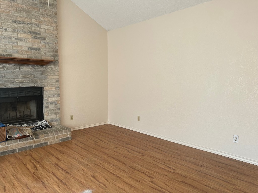 12308 A Los Indios Trail Austin, TX 78729 - Photo 2 of 19 a view of an empty room with wooden floor and a fireplace