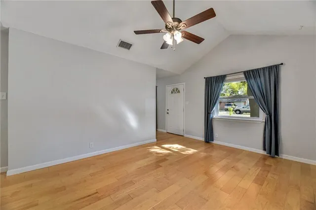 an empty room with windows and fan