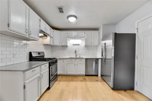 a kitchen with stainless steel appliances granite countertop a refrigerator and a stove
