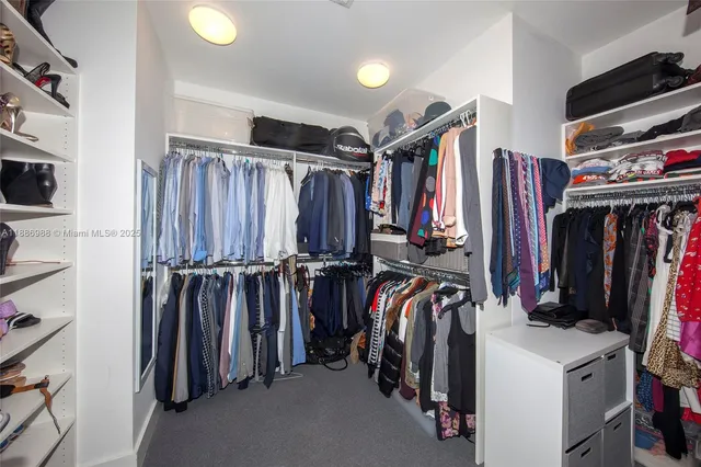 a view of walk in closet with clothes and shoes
