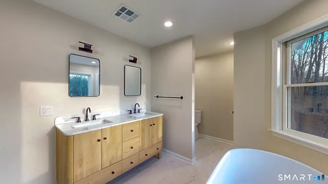 a en suite bathroom with 2 sink tub and a mirror