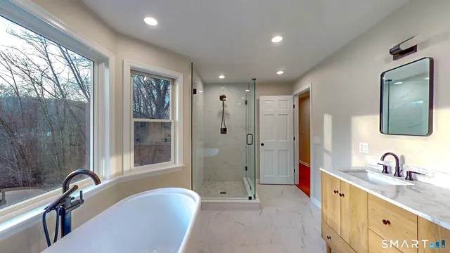 a bathroom with a tub sink double vanity and a mirror