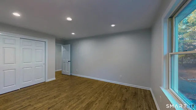 an empty room with wooden floor and windows