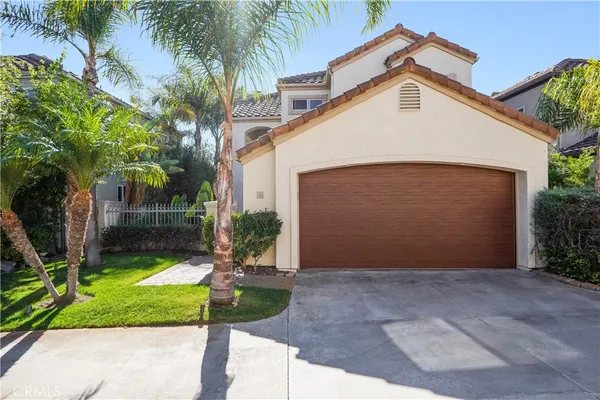 a view of a white house with a small yard and palm trees