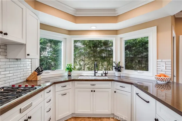a kitchen with sink a large window and cabinets