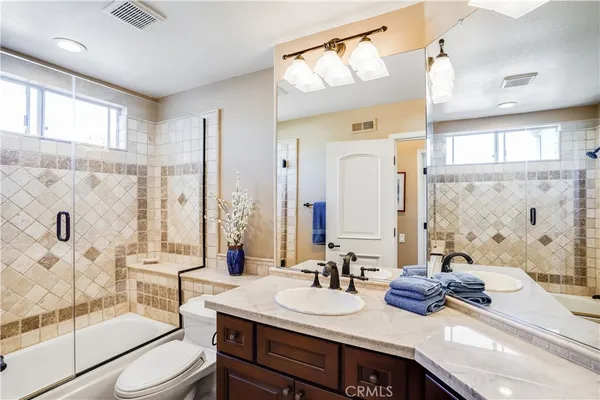 a bathroom with double vanity sinks a toilet a mirror and shower