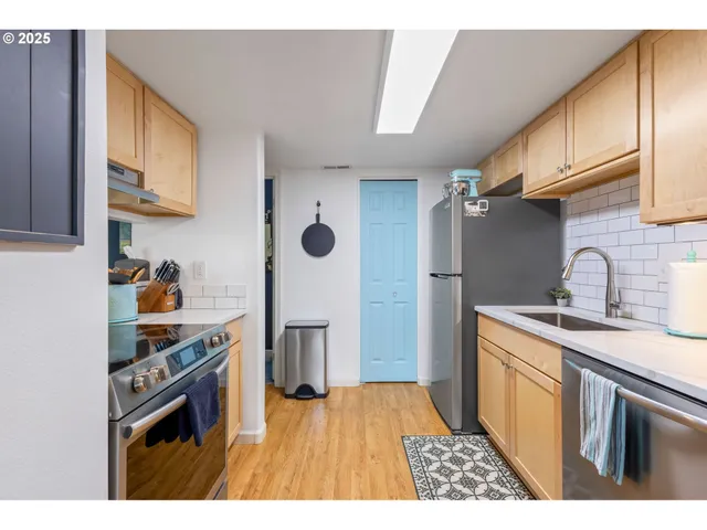 a kitchen with stainless steel appliances granite countertop a stove a sink dishwasher a refrigerator and cabinets with wooden floor