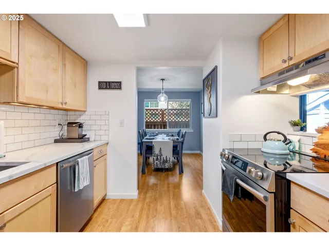 a kitchen with stainless steel appliances granite countertop a stove a sink dishwasher and cabinets with wooden floor