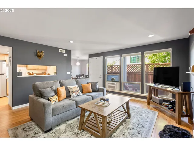 a living room with furniture a flat screen tv and a floor to ceiling window