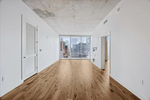 a view of an empty room with wooden floor and a window