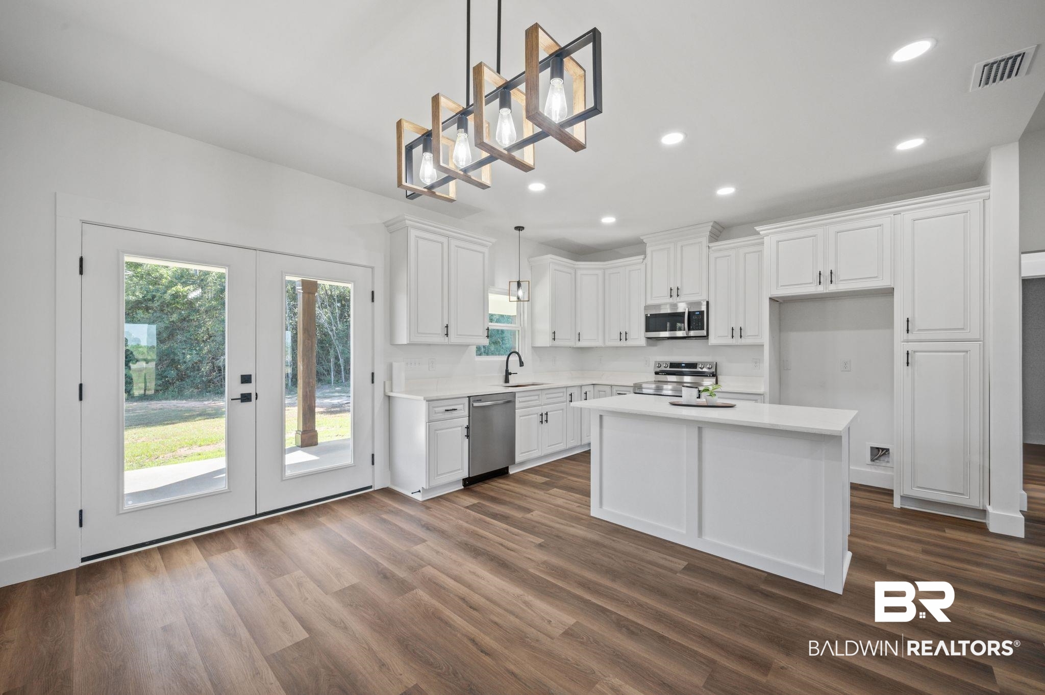 12100 Lott Road Chunchula, AL 36521 - Photo 6 of 21 Kitchen with dark wood-type flooring, hanging light fixtures, stainless steel appliances, and white cabinets