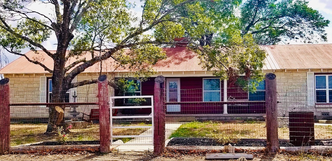 a view of a house with a yard tree and a wooden fence