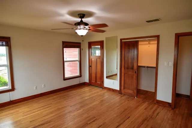 a view of an empty room with wooden floor and a window
