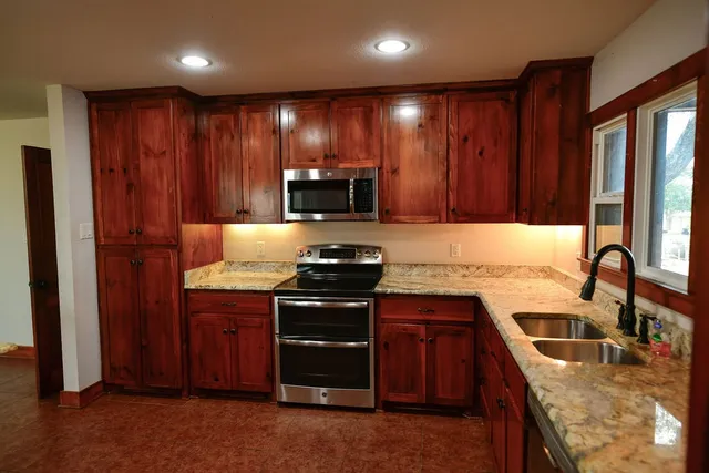 a kitchen with granite countertop a sink stove and cabinets