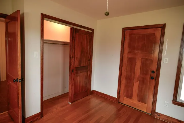 a view of an empty room with window and wooden floor