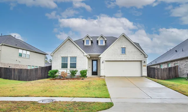 a view of a house with a yard plants and large tree