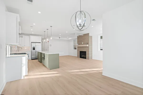 a kitchen with stainless steel appliances a sink a stove a refrigerator and chairs
