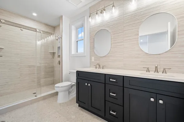 a bathroom with a double vanity sink toilet mirror and shower