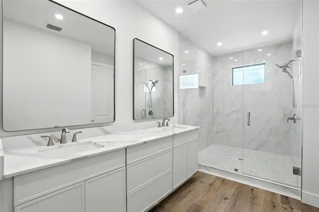 a bathroom with a double vanity sink mirror and shower
