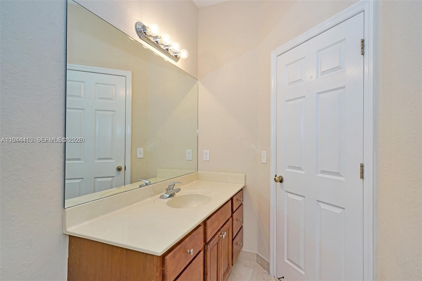 1048 Northeast 208th Street Miami, FL 33179 - Photo 24 of 36 a bathroom with a sink vanity and a mirror