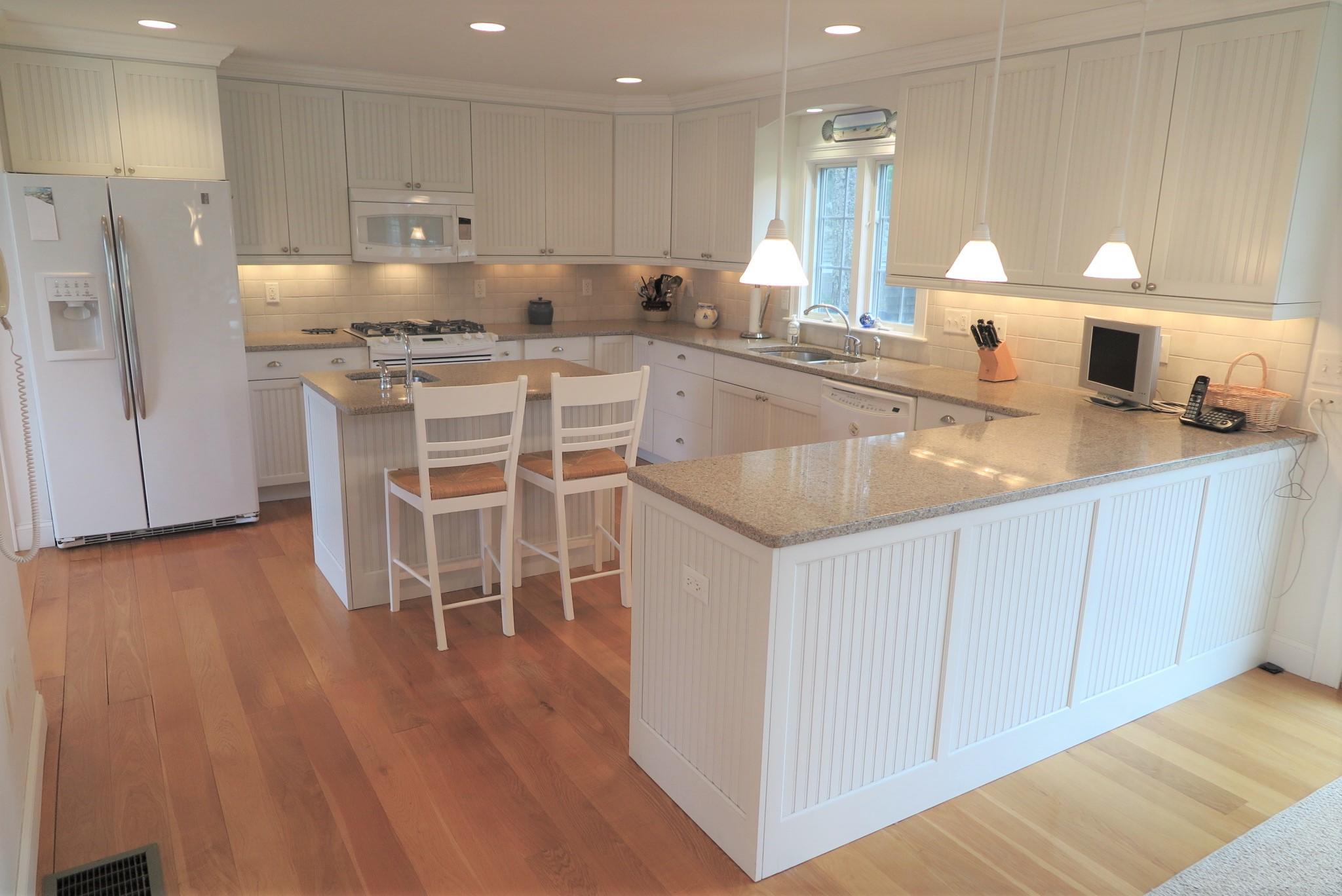 79 Shore Road West Dennis, MA 02670 - Photo 12 of 42 a kitchen with stainless steel appliances granite countertop a sink a stove a refrigerator and white cabinets with wooden floor