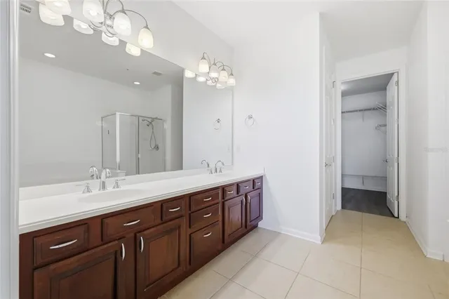 a spacious bathroom with a double vanity sink a large mirror and a shower