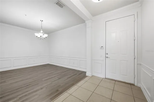 an empty room with wooden floor and chandelier