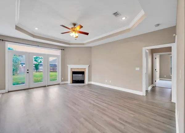 a view of an empty room with a window and wooden floor
