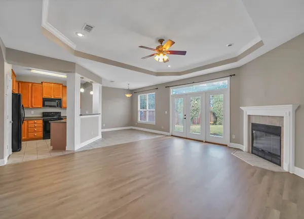 an empty room with wooden floor fireplace and windows