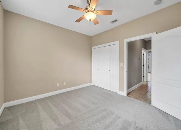 an empty room with closet and a chandelier fan