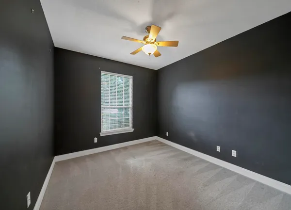 an empty room with window and chandelier fan