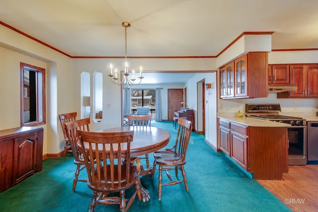 a dining room with furniture a chandelier and kitchen view