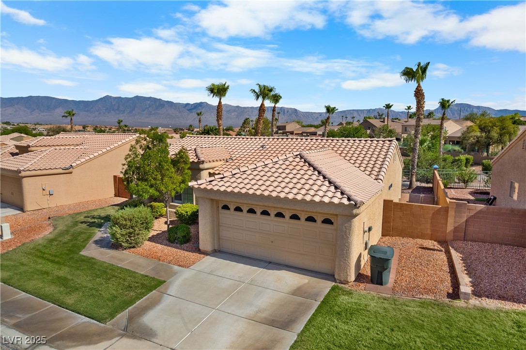 490 Ruby Drive Mesquite, NV 89027 - Photo 19 of 23 Mediterranean / spanish-style home with stucco siding, a residential view, a tile roof, a mountain view, and concrete driveway