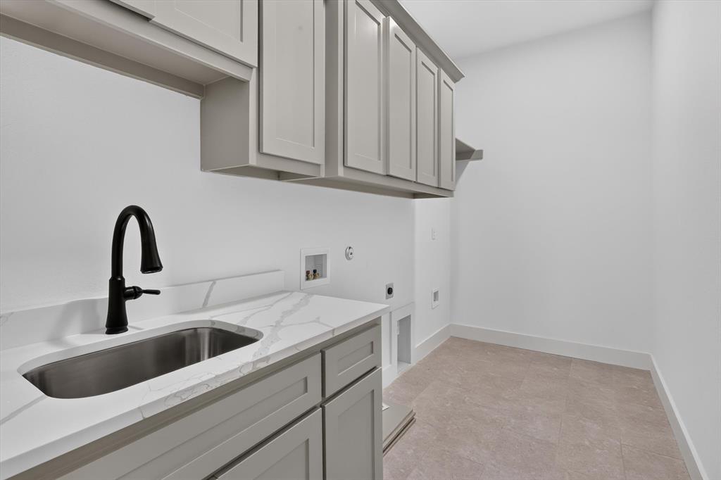 471 Red Bird Drive Springtown, TX 76082 - Photo 30 of 35 Utility room featuring a built-in sink with a matte black faucet, light gray cabinetry, white countertops with veining, and neutral tile flooring