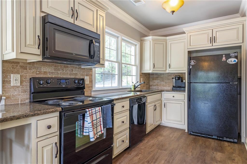 6026 GC Crow Road Flowery Branch, GA 30542 - Photo 73 of 100 a kitchen with granite countertop a refrigerator stove and microwave