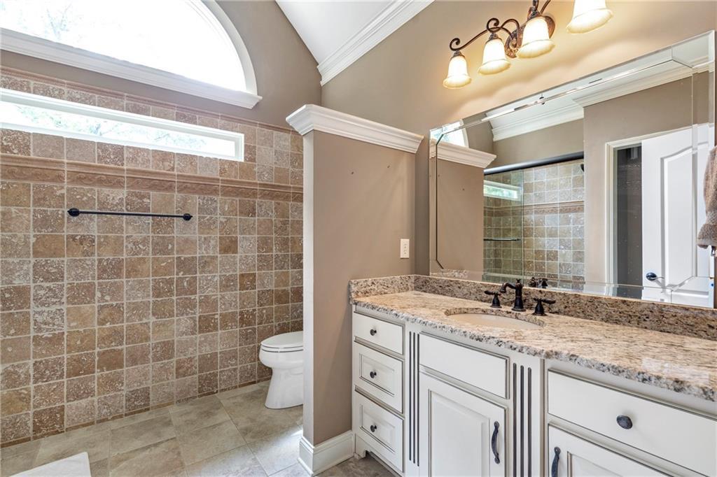 6026 GC Crow Road Flowery Branch, GA 30542 - Photo 79 of 100 a bathroom with a granite countertop sink a toilet a mirror and shower